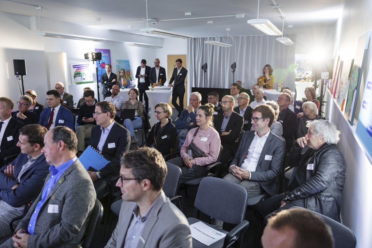 Einweihungsempfang Gäste Zahlreiche Gäste sitzen auf Stühlen in einem Raum und sehen Richtung Bühne, die nicht im Bild ist.